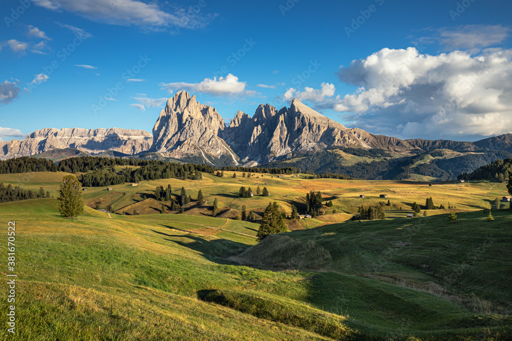 Naklejka premium Famous Alpe di Siusi - Seiser Alm with Sassolungo - Langkofel mountain group in background at sunset. Wooden chalets in Dolomites, Trentino Alto Adige region, South Tyrol, Italy