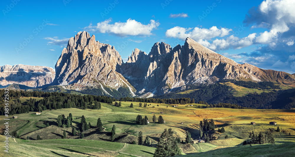 Famous Alpe di Siusi - Seiser Alm with Sassolungo - Langkofel mountain group in background at sunset. Wooden chalets in Dolomites, Trentino Alto Adige region, South Tyrol, Italy