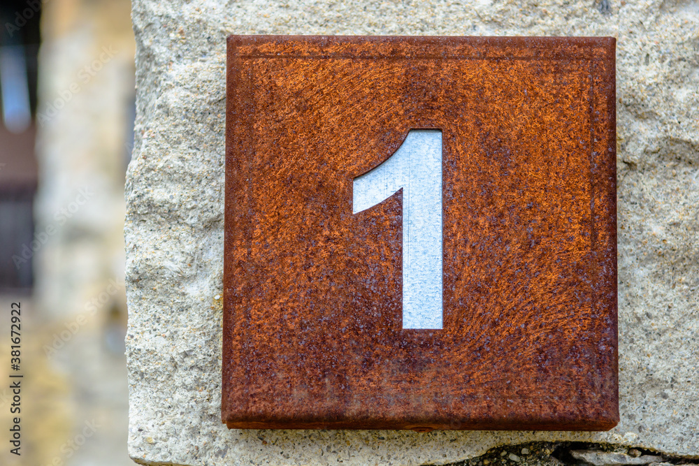 Number one on a rusted squared house sign Number one on a rusted squared house sign