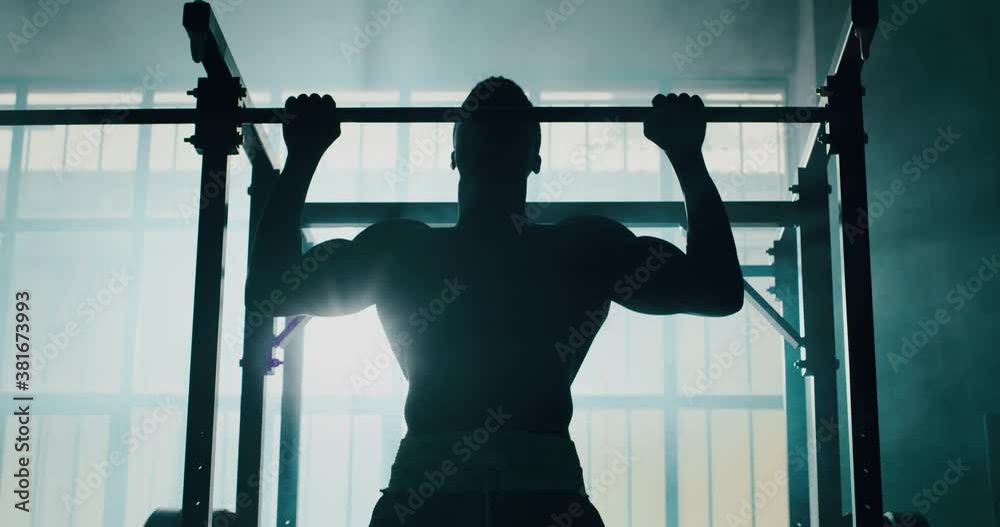 Cinematic slow motion shot of a professional young muscular shirtless african man is practicing shadow boxing work out in a gym with ring. 
