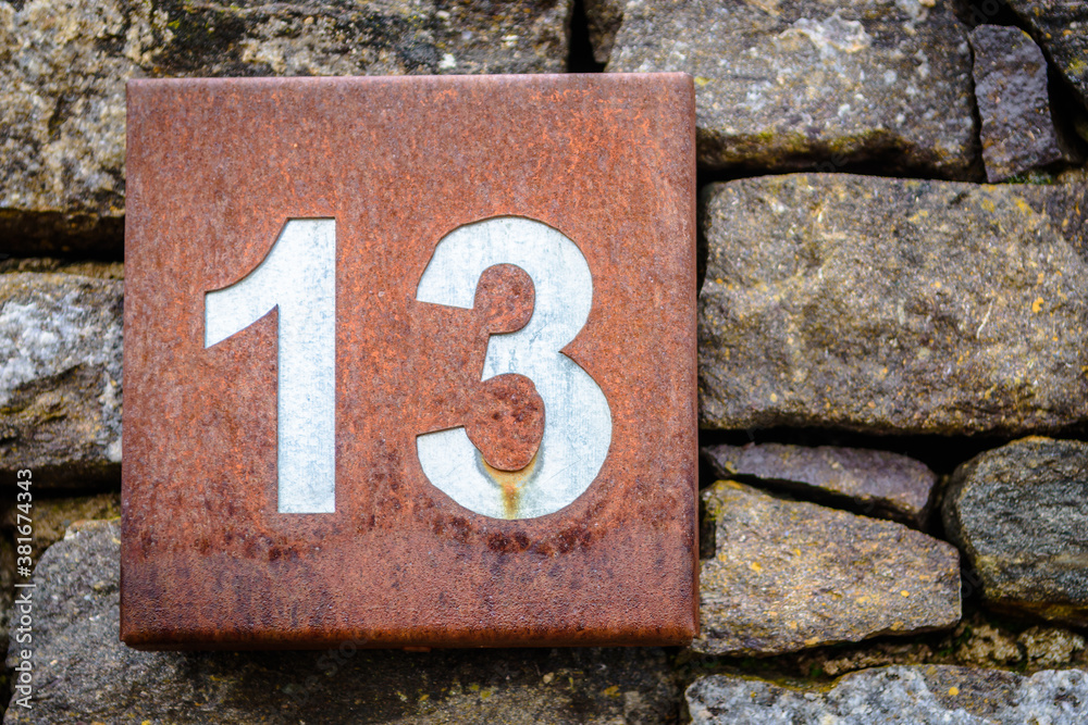 Number thirteen on a rusted squared house sign Number thirteen on a rusted squared house sign