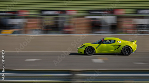 A panning shot of a green racing car as it circuits a track.