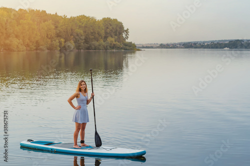 Young woman floats on the water of the lake on a sap board with an oar