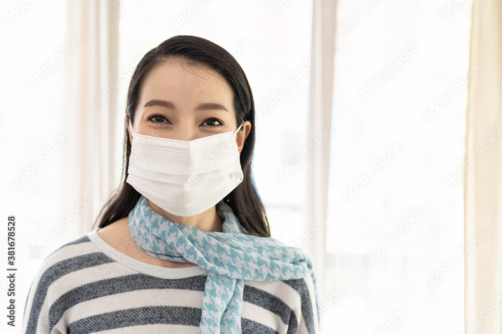 Young Asian woman wearing protective medical face mask at home during quarantine coronavirus or COVID-19 outbreak. Health and medical concept. Young Asian woman wearing protective medical face mask at home during quarantine coronavirus or COVID-19 outbreak. Health and medical concept.