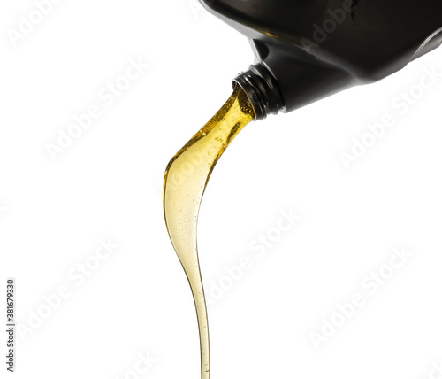 Pouring fresh automotive engine oil (lubricating oil, yellow liquid oil) into a motor car isolated on white background. Change new oil. Maintenance, service, and energy fuel concept. .