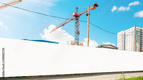 long hoarding with empty space for mock up on construction site red crane and blue sky background photo