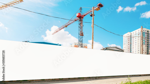 long hoarding with empty space for mock up on construction site red crane and blue sky background