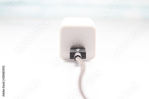 White charger adapter and black USB cable on a white background The concept of charging technology to power mobile phones