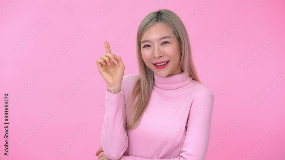 Cheerful excited young woman pointing finger at copy space on pink background 4k resolution Cheerful excited young woman pointing finger at copy space on pink background 4k resolution