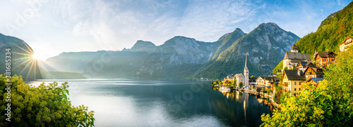 Panorama view of famous old town Hallstatt and alpine deep blue lake with tourist ship in scenic golden morning light on a beautiful sunny day at sunrise in summer, Salzkammergut, Austria