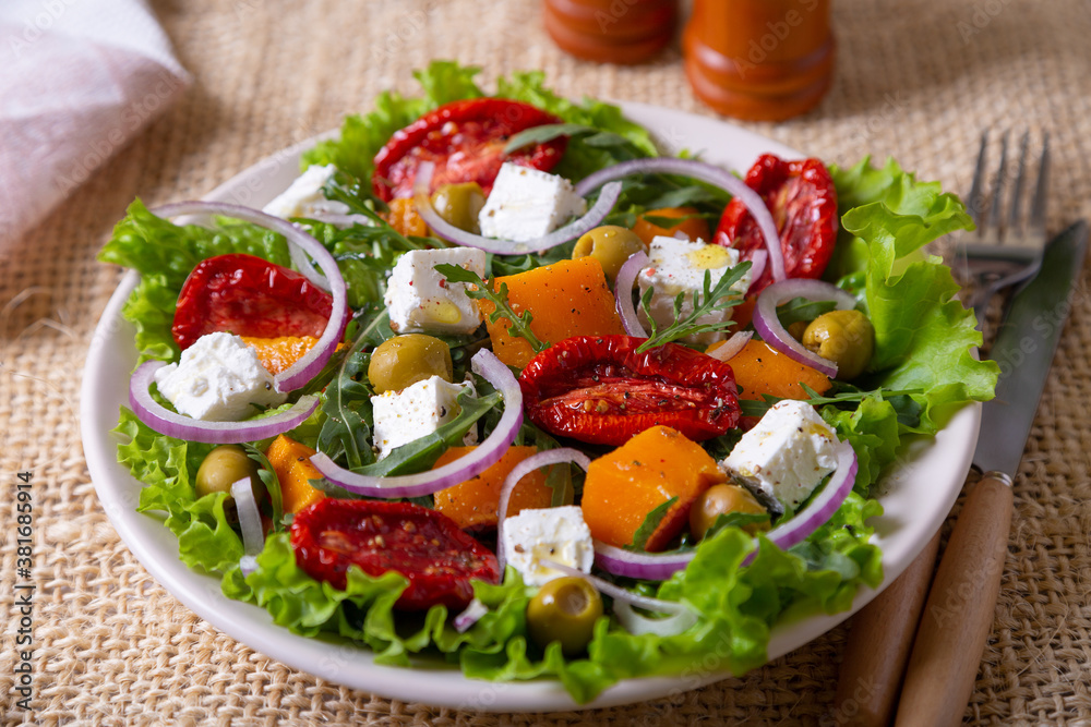 Warm salad with pumpkin, feta cheese, sun-dried tomatoes, olives, arugula and red onion. Close-up. Warm salad with pumpkin, feta cheese, sun-dried tomatoes, olives, arugula and red onion. Close-up.