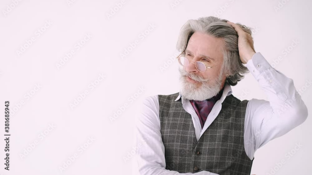 A senior man in tux standing against white background. Brutal stylish man is touching his hair. A senior man in tux standing against white background. Brutal stylish man is touching his hair.