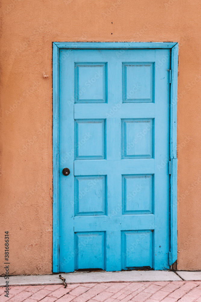 Abstract old light blue door in orange textured building
