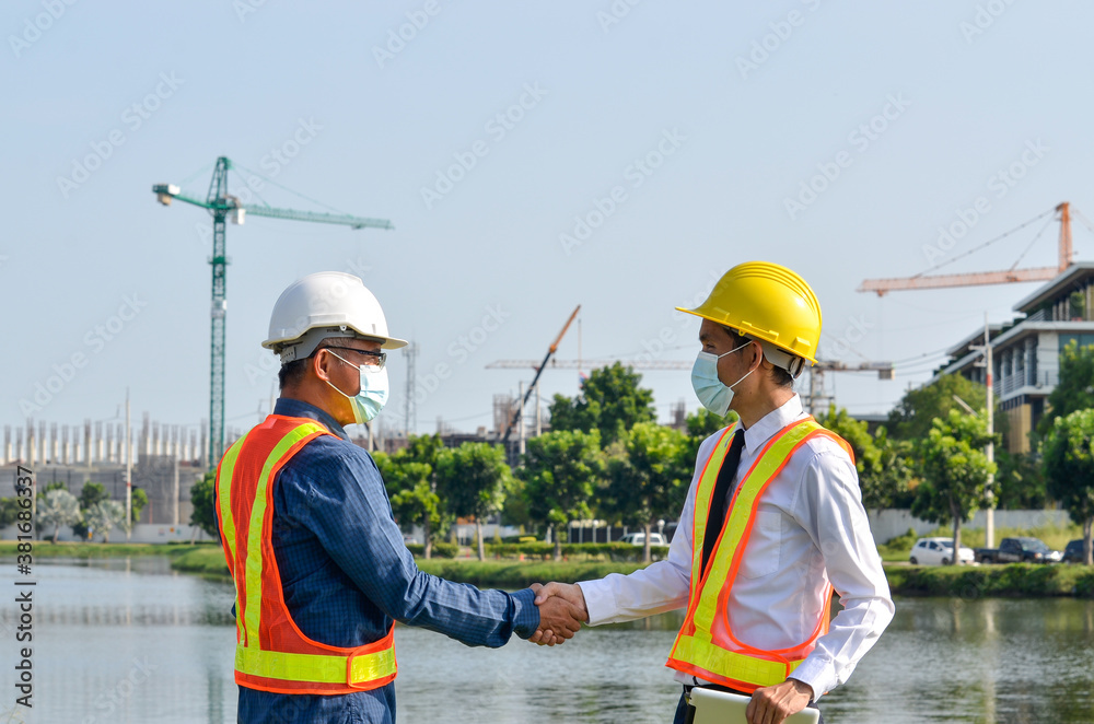 Two engineers shake hands at a building project.