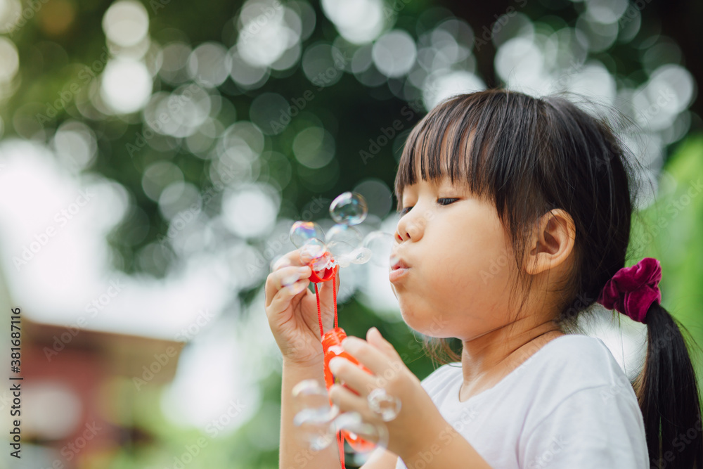 Cute kid blowing bubbles soap in the garden. Concept of digital free or unplugged outdoors activity for children.