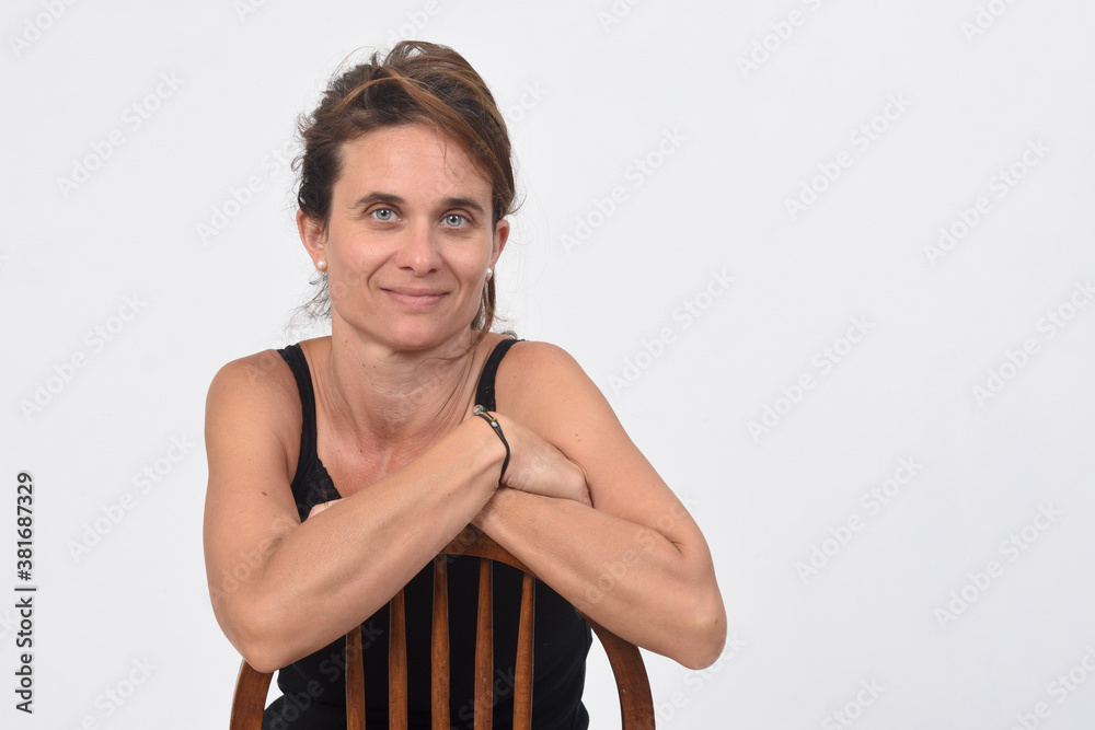 portrait of a 40 year old woman without makeup on white background, sitting on a chair and looking at camera portrait of a 40 year old woman without makeup on white background, sitting on a chair and looking at camera