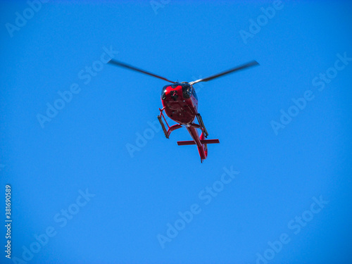 A helicopter flies in the sky. Some of helicopter uses are transportation of people and cargo, search and rescue, tourism, medical transport, news and media, and aerial observation, among others. photo