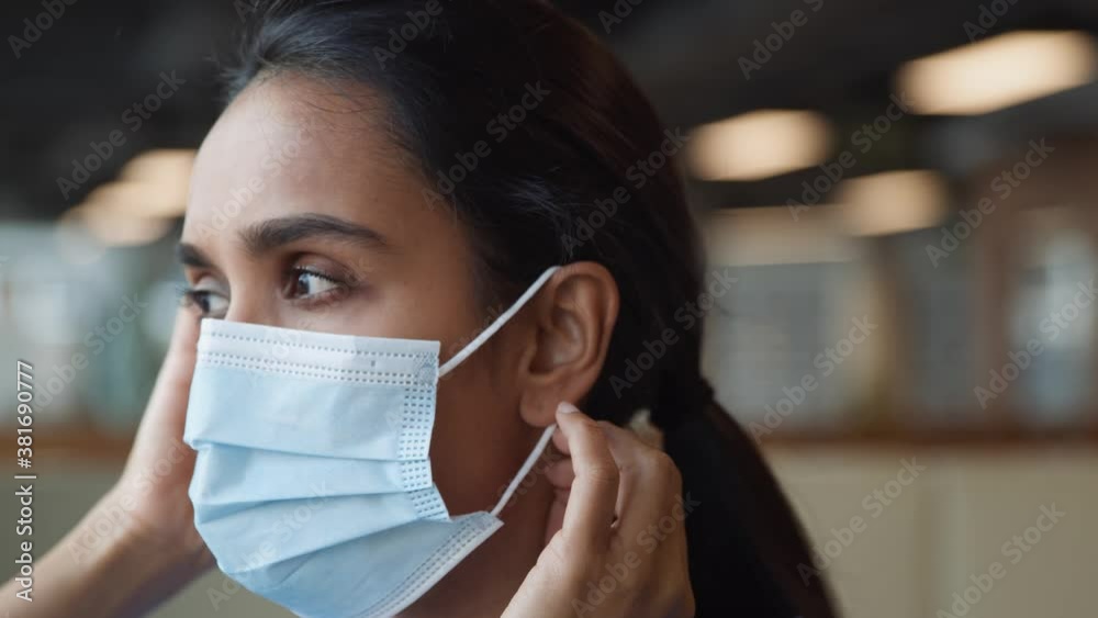 Portrait Of Nurse In Scrubs Putting On Face Mask In Busy Hospital During Health Pandemic Portrait Of Nurse In Scrubs Putting On Face Mask In Busy Hospital During Health Pandemic