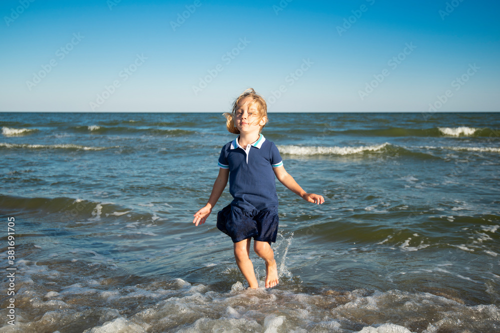Little girl in a blue dress running and having fun on the beach