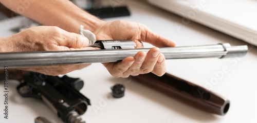 man's hands holding rifle parts details and cleaning the gun