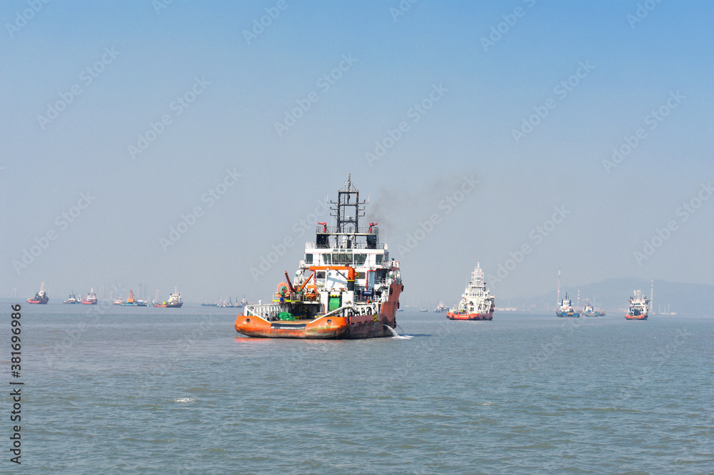 A orange rescue boat floating in the vast blue water in mumbai
