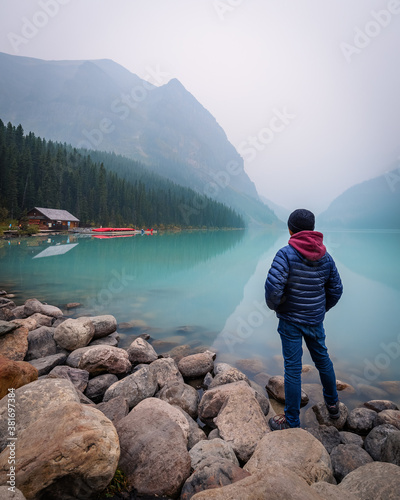 A man standing over the rocks at the shore of Lake Louise on a smoke filled afternoon (Banff, Alberta, Canada) © Salvador Maniquiz