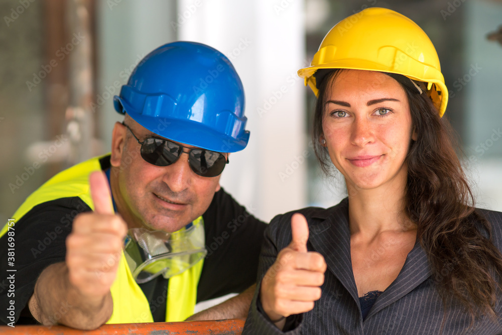 Positive emotions: enjoying the teamwork. Cheerful and smiling construction workers posing showing thumbs up gesture Positive emotions: enjoying the teamwork. Cheerful and smiling construction workers posing showing thumbs up gesture