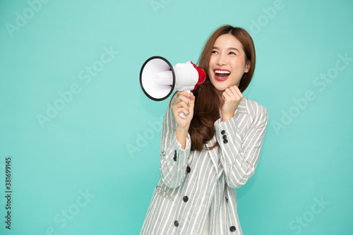 Принти на полотні Young Asian woman holding megaphone isolated on green background, Speech and ann