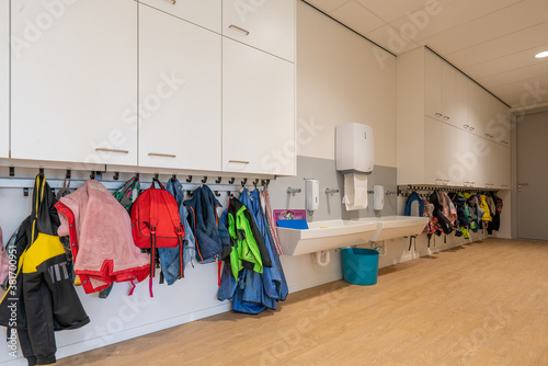 Fototapeta ARNHE, NETHERLANDS - Aug 28, 2020: Cloakroom with coats and backpacks in a schoo