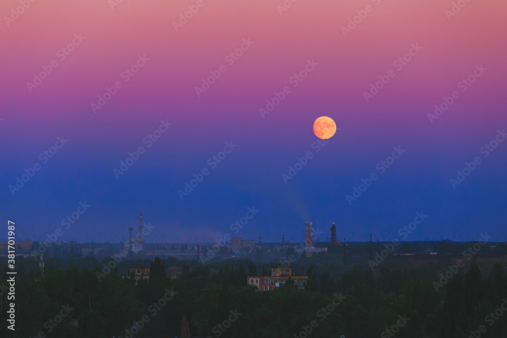 Full moon on the pink sky rise over the city and factory