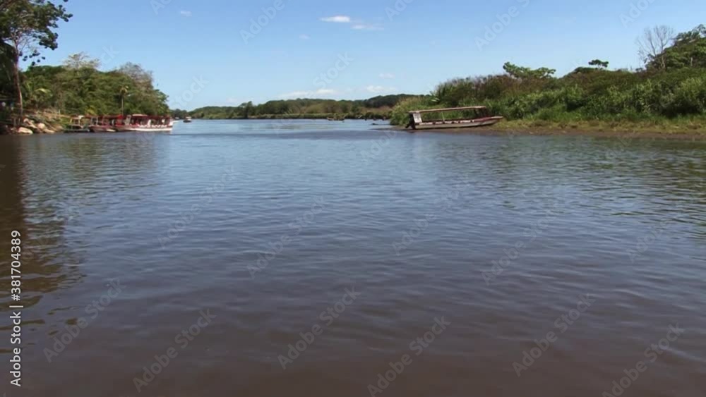 Wide shot of Tarcoles river in Costa Rica and the rain forest around, boats waiting for tourists by the river bank. Wide shot of Tarcoles river in Costa Rica and the rain forest around, boats waiting for tourists by the river bank.