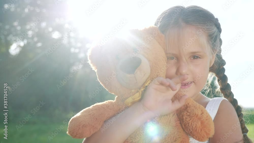little kid girl hugging a teddy bear toy portrait in the park in nature ...
