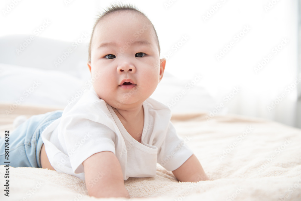 Portrait of a crawling baby on the bed. Happy asian infant in bedroom.