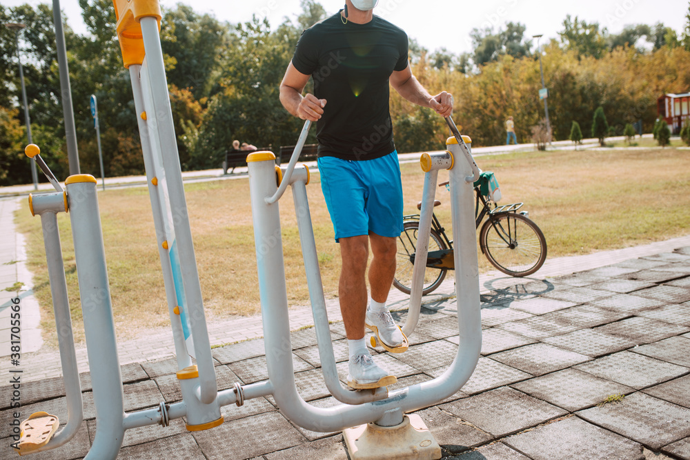 Fototapeta premium Close-up of a handsome male caucasian athlete training on a stepper in the outdoor gym. Muscular athlete outdoors.