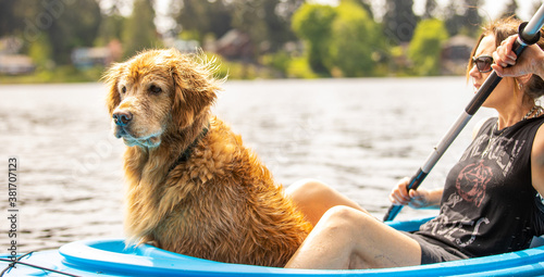 A woman and a golden retriever dog on a blue kayak over a lake