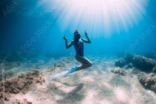 Happy freediver woman with New year cap glides underwater in blue ocean. Christmas holiday concept