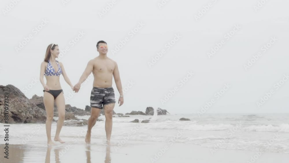 Young asian couple walking on beach with love romantic honeymoon in vacation, girlfriend and boyfriend running relax on sea shore in summer trip with happy and cheerful together, slow motion. Young asian couple walking on beach with love romantic honeymoon in vacation, girlfriend and boyfriend running relax on sea shore in summer trip with happy and cheerful together, slow motion.