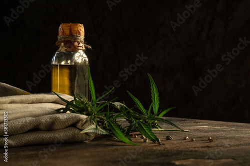 Hemp oil, textile and cannabis plant on wooden table