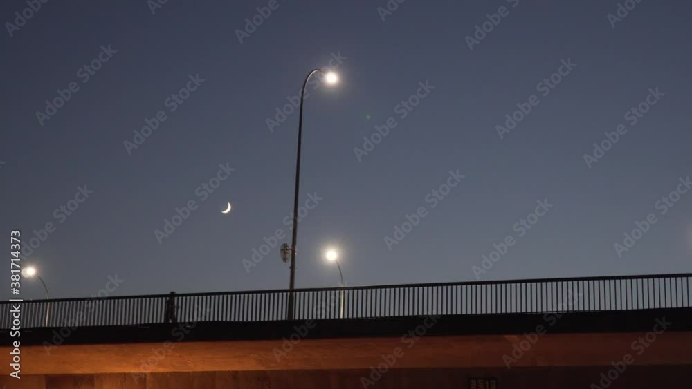 Distant view of people silhouette walking along the bridge alone at night at moonlight time, low angle wide shot