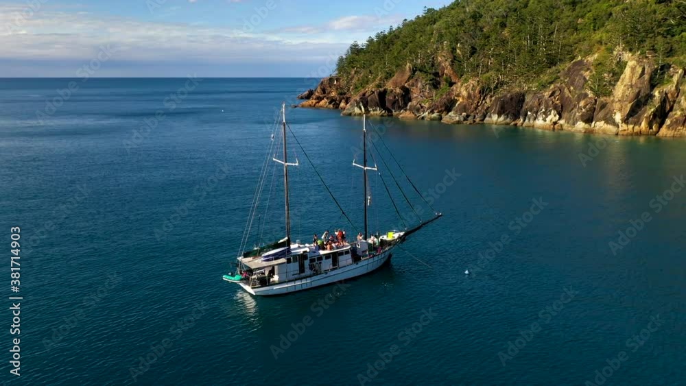 Rotating drone shot of sailboat in bay at Hook Island with people on deck. Near Whitsunday Island Australia Rotating drone shot of sailboat in bay at Hook Island with people on deck. Near Whitsunday Island Australia