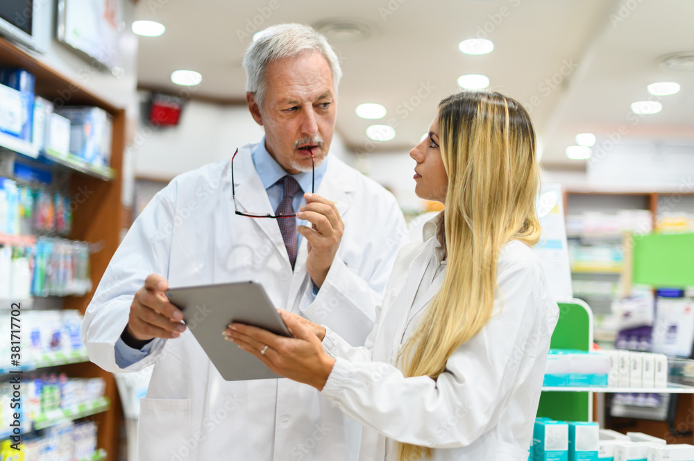 Two pharmacists talking while working on tablet in their store