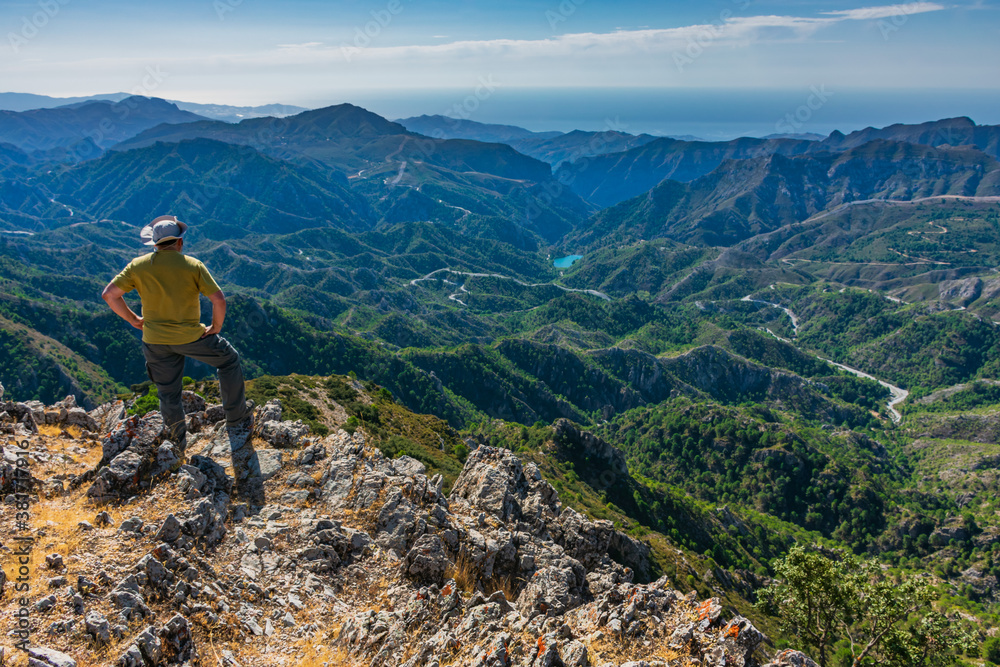 Hiker on a mountain peak looking at the landscape in front of him