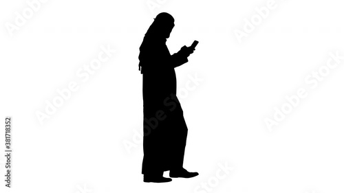 Arab man using his smartphone surfing on the internet or messaging while walking, Alpha Channel photo