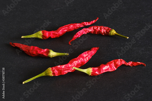 Dry chilli peppers scattered on black background