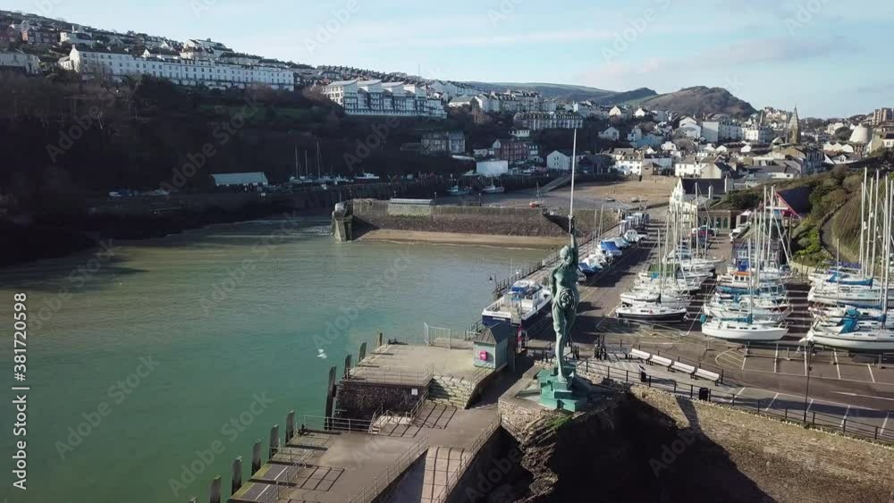 Seaside Resort Town Of Ilfracombe From The Verity Statue Stands On The Pier At The Entrance To The Harbor - North Devon Coast, England, United Kingdom. - aerial pullback shot Seaside Resort Town Of Ilfracombe From The Verity Statue Stands On The Pier At The Entrance To The Harbor - North Devon Coast, England, United Kingdom. - aerial pullback shot