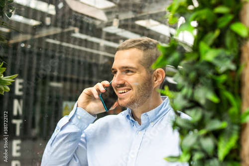 Obraz na płótnie Photo of a young and attractive business man wearing smart casual and elegant clothes talking on the phone while smiling. Smart working. Entrepeneur w salonie