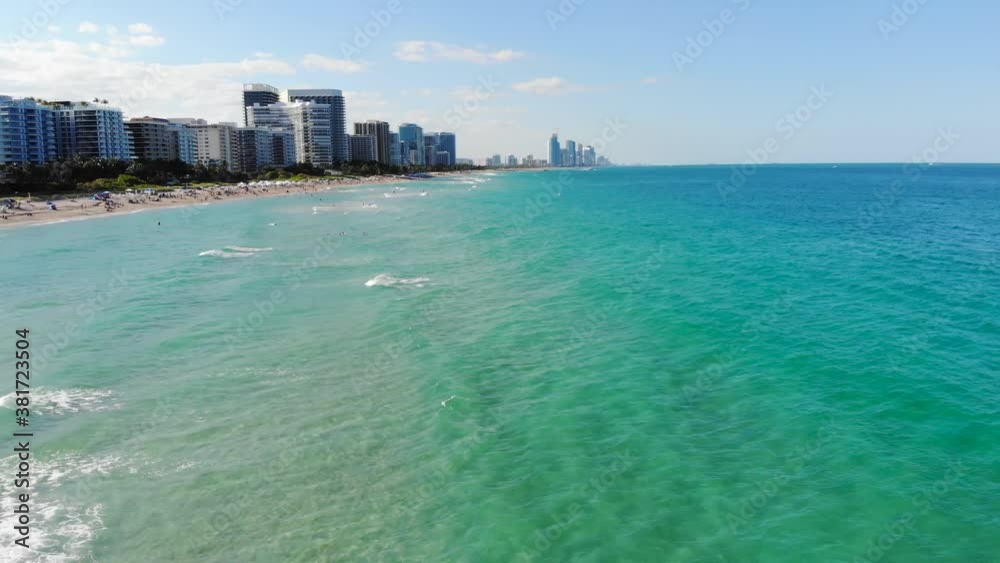 Ocean waves coming in calmly over western society beach with high rise modern buildings Ocean waves coming in calmly over western society beach with high rise modern buildings