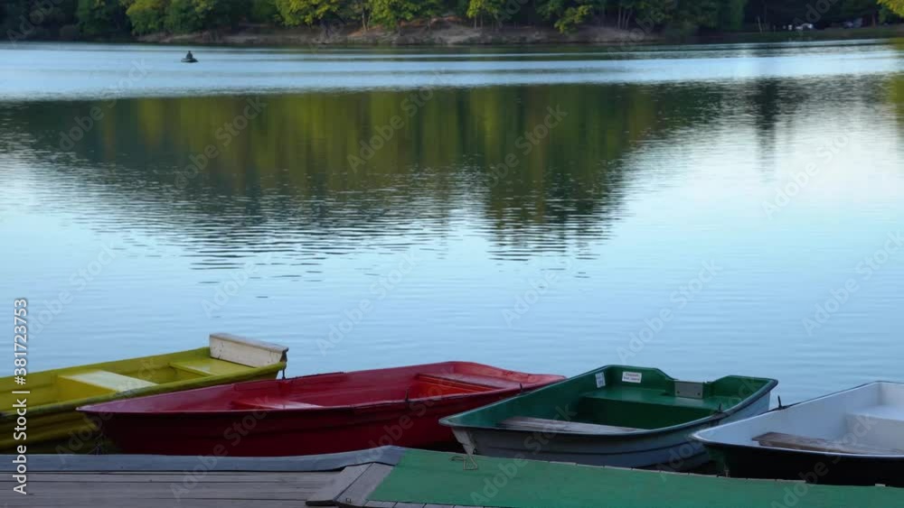Colorful boats docking on the side of the calm lake on summer evening sunset. Colorful boats docking on the side of the calm lake on summer evening sunset.