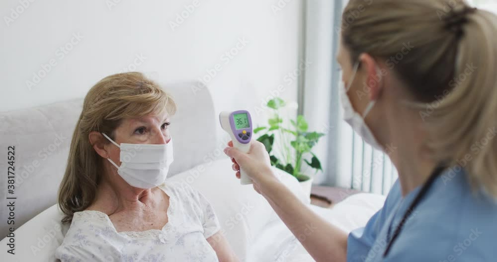 Female health worker checking temperature of senior woman at home Female health worker checking temperature of senior woman at home