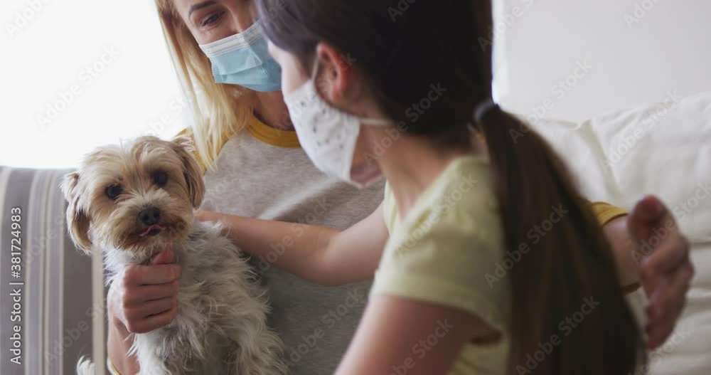 Mother and daughter wearing face masks hugging their pet dog at home Mother and daughter wearing face masks hugging their pet dog at home